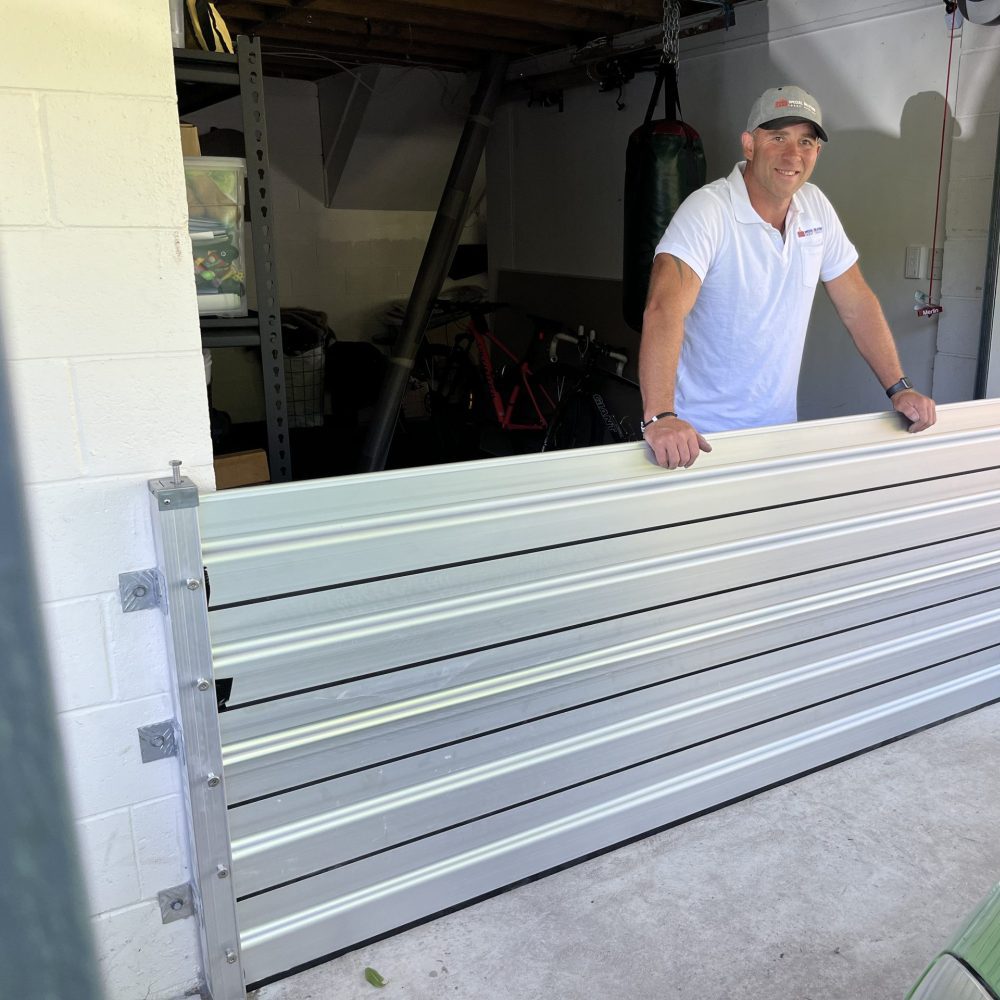 Allan McLean standing beside an installed aluminium garage barrier