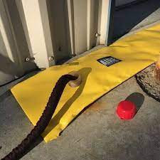 Hose inserted into the filling opening of a yellow flood barrier