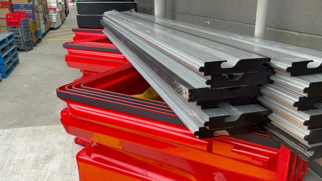Removable aluminium flood-barrier panels stacked with red FloodBloc units at Mount Albert New World