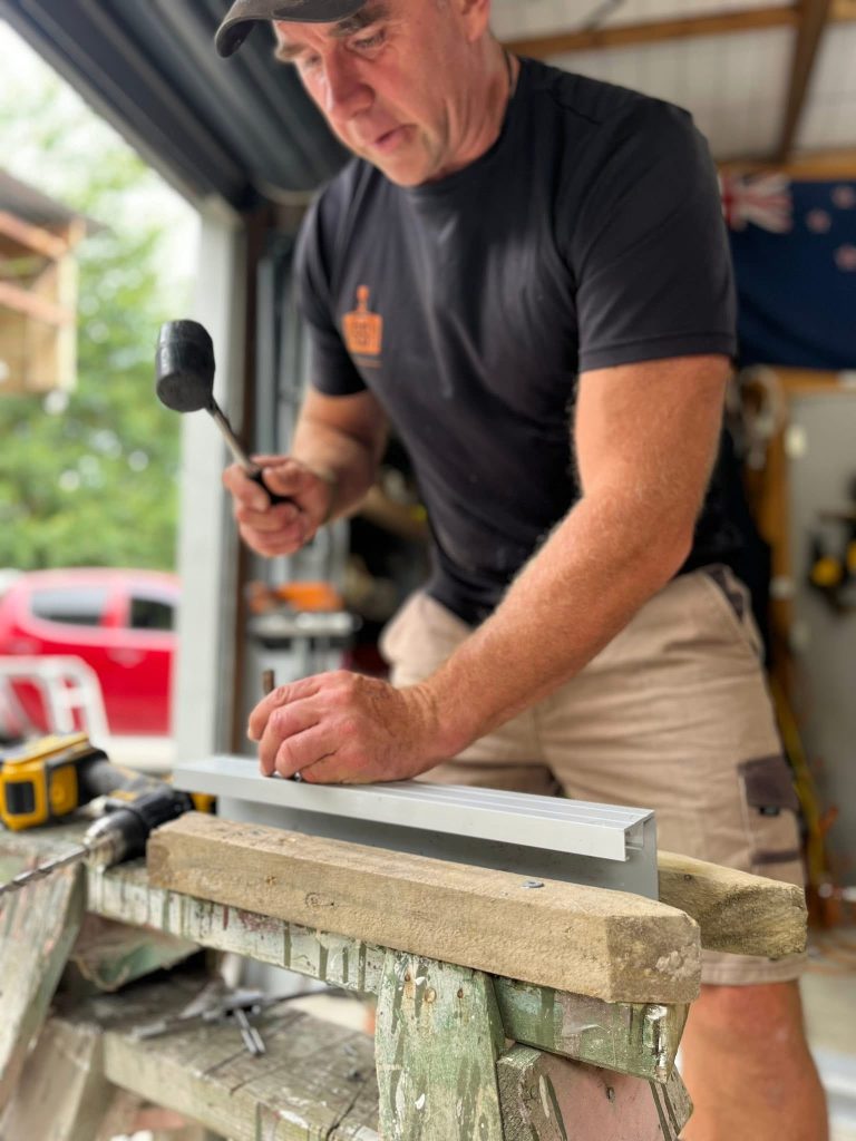 Allan McLean assembling a removable aluminium flood barrier for a New Zealand home