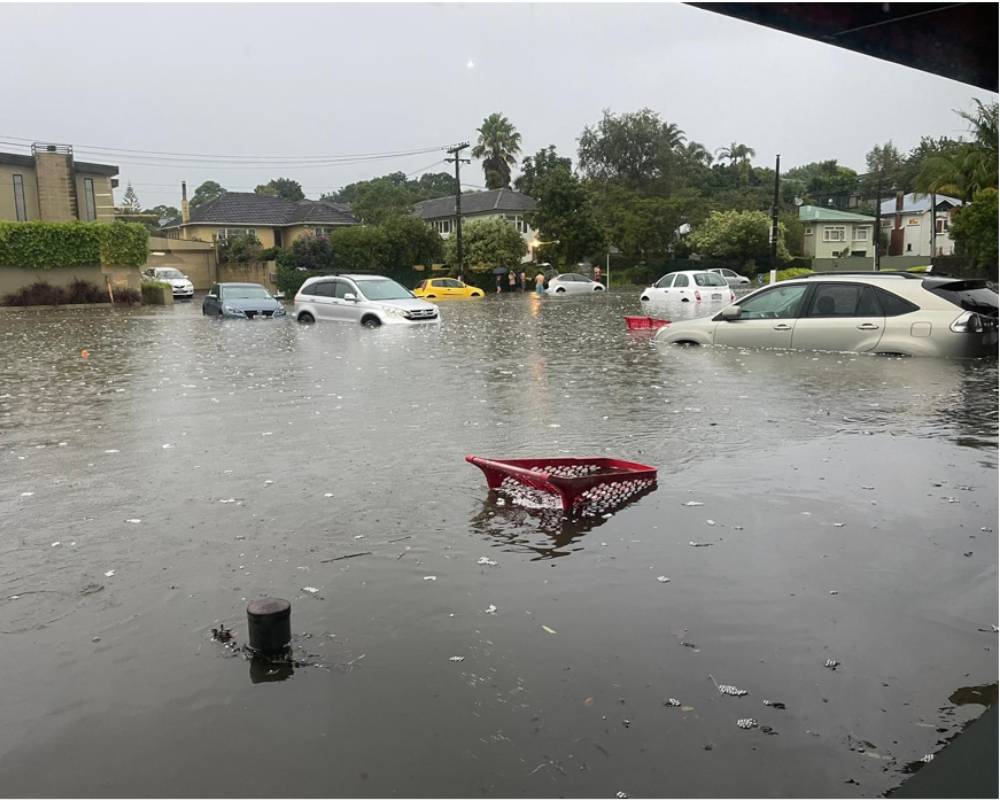 Cars and a shopping trolley surrounded by deep floodwater in the Mount Albert supermarket car park in January 2023